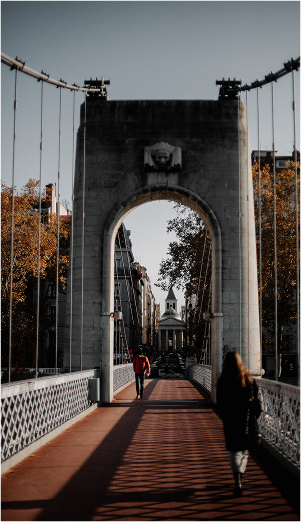 Pont pittoresque avec des passants et des arbres dorés.