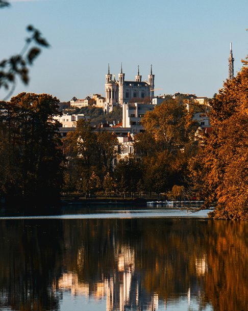 Vue d'un château au bord d'un lac, sous un ciel bleu.