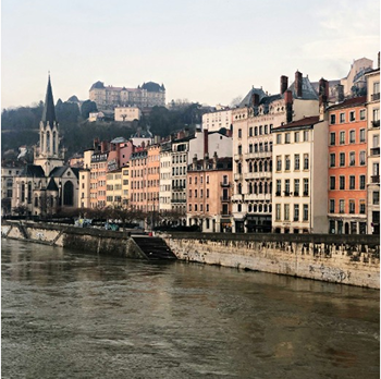 Rives du Rhône à Lyon, bâtiments colorés et montagne en arrière-plan.